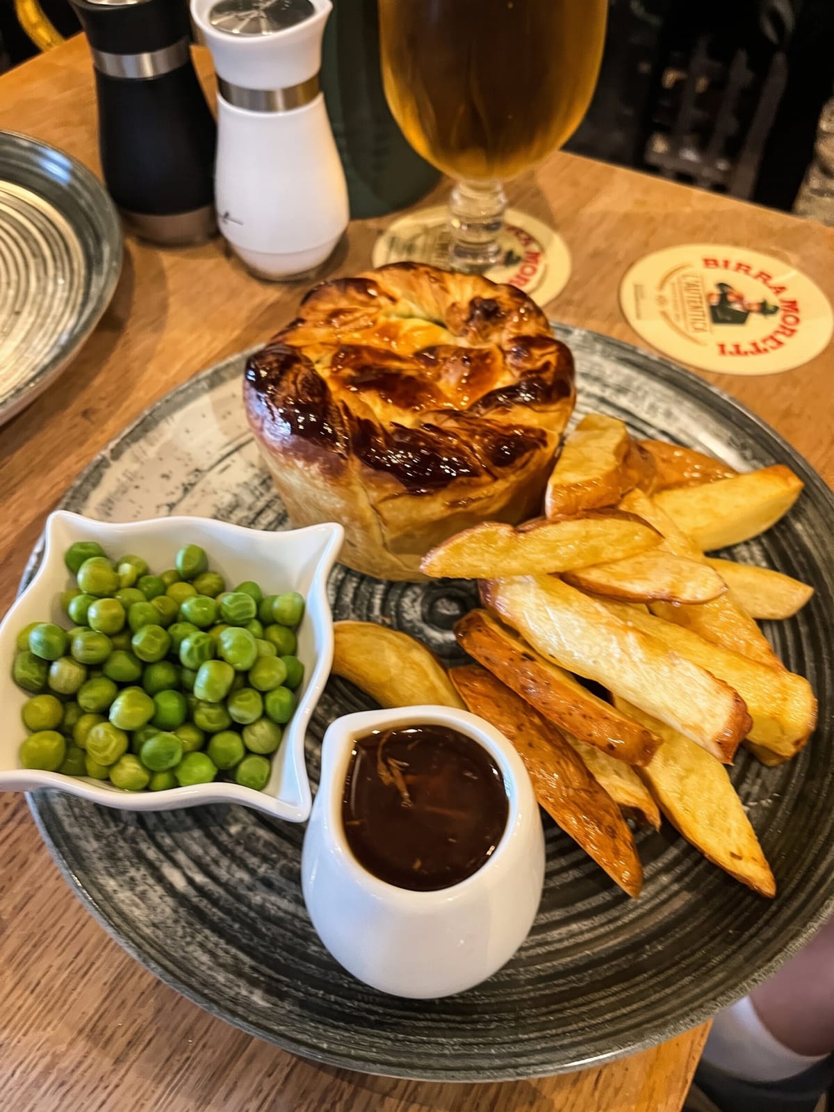 A homemade pie with chips, peas and gravy