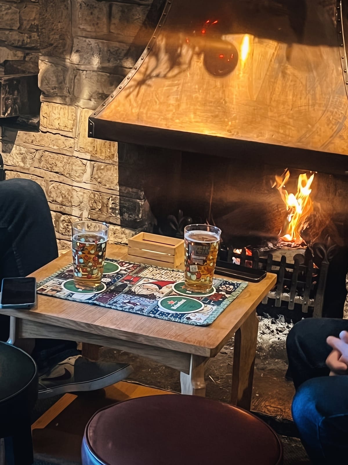 Two pints on a table by the open fire